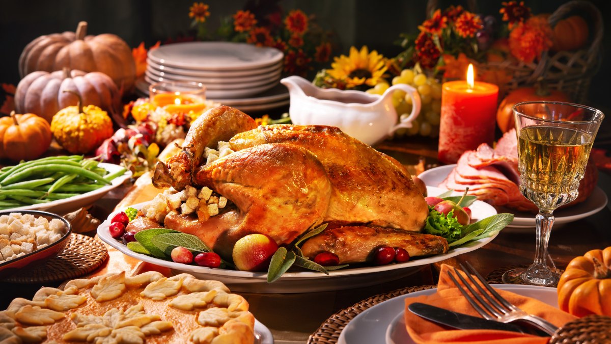 Thanksgiving Dinner Buffet Roast turkey with stuffing, sliced ham, green beans and pie on a fall Thanksgiving table