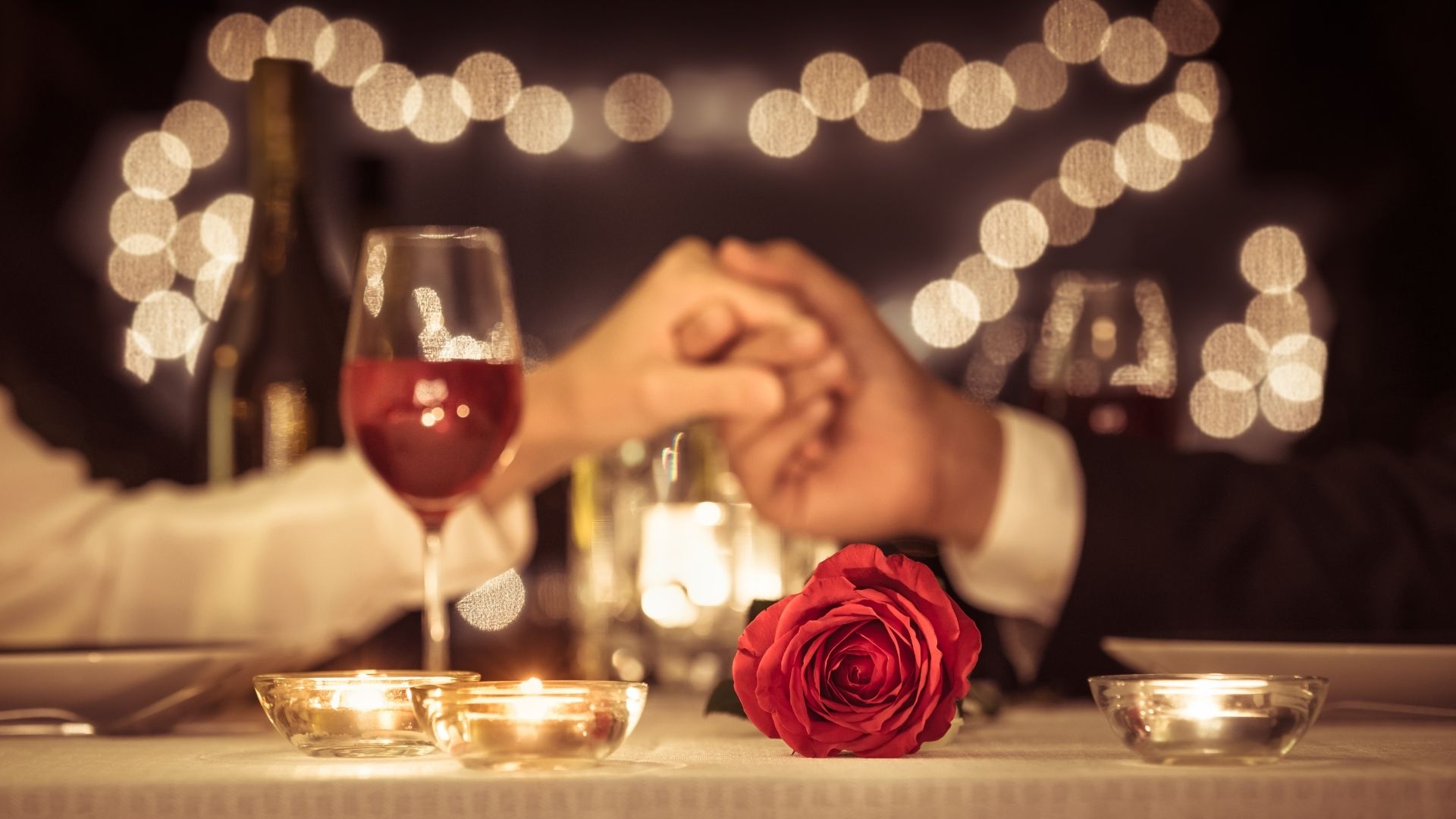 couple holding hands, dinner, rose, wine